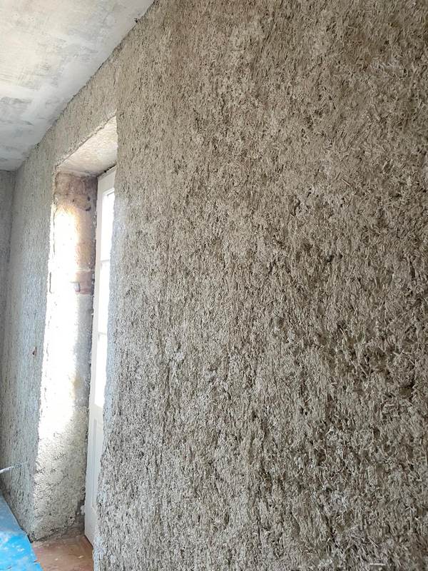 Texture d'un enduit chaux-chanvre isolant, près d'une ouverture
